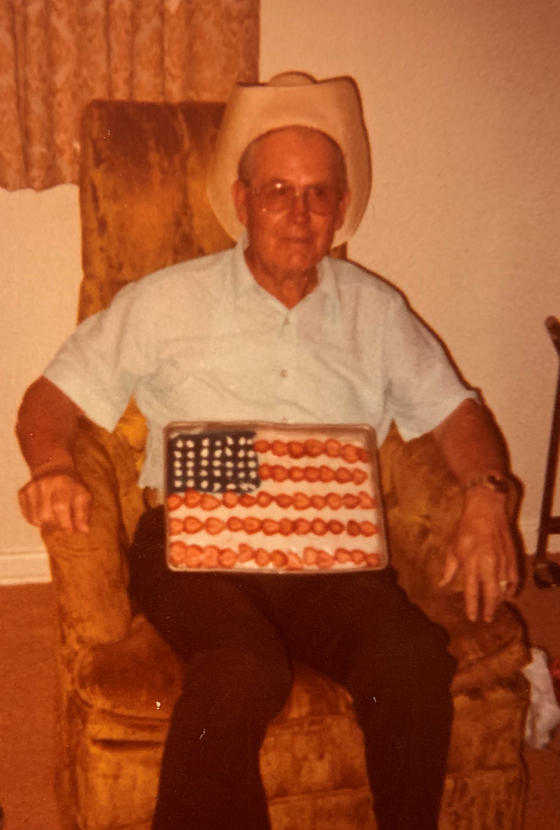 An old person sitting in a chair holding a tray of food  Description automatically generated